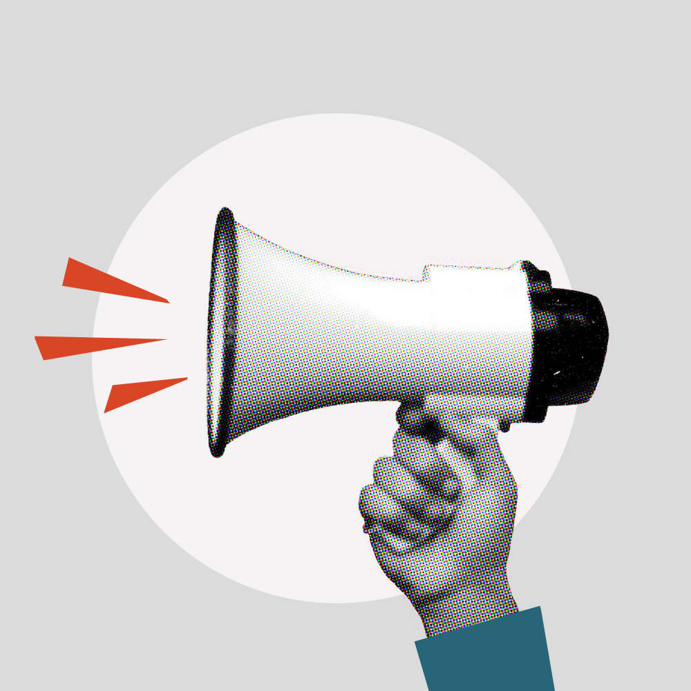 Hand holding megaphone in front of bright red background during a protest rally